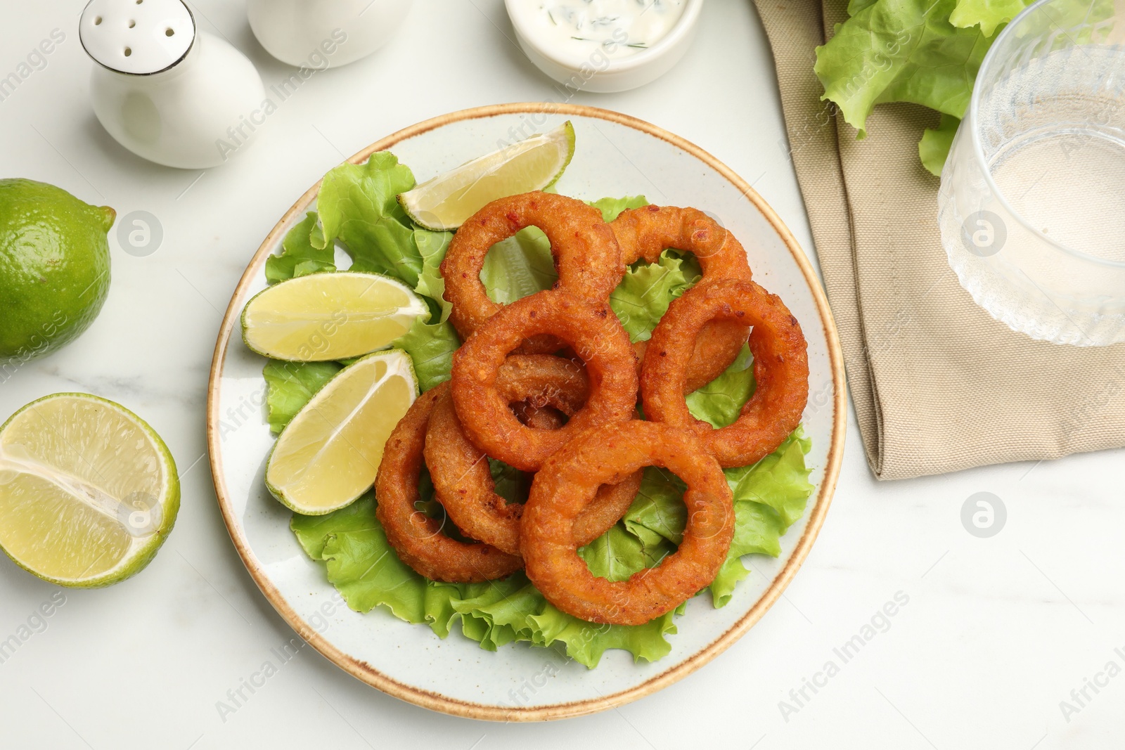 Fried squid rings served on white marble table, flat lay Photo of Fried squid rings served on white marble table, flat lay
