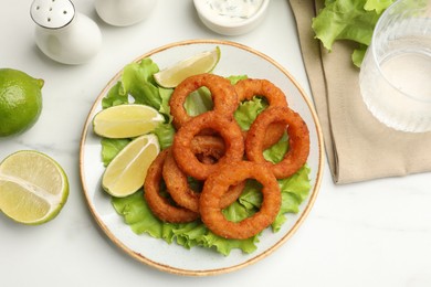 Photo of Fried squid rings served on white marble table, flat lay