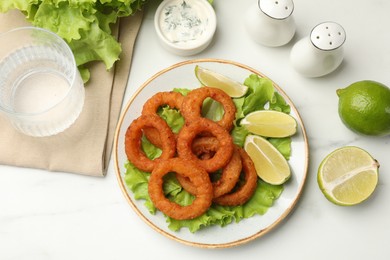 Photo of Fried squid rings served on white marble table, flat lay