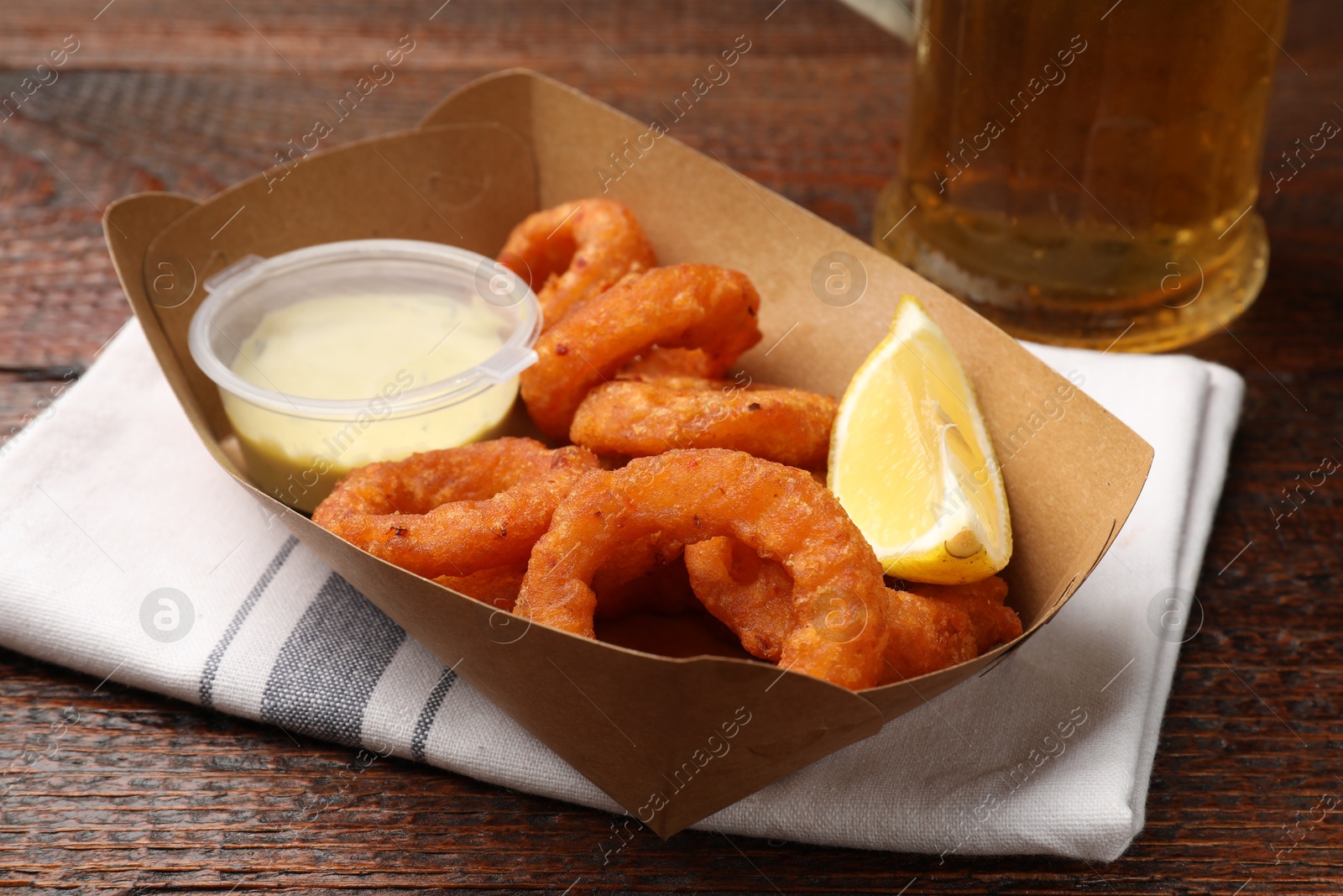 Fried squid rings, lemon, sauce and beer on wooden table, closeup Photo of Fried squid rings, lemon, sauce and beer on wooden table, closeup