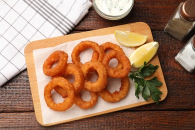 Photo of Fried squid rings served on wooden table, flat lay