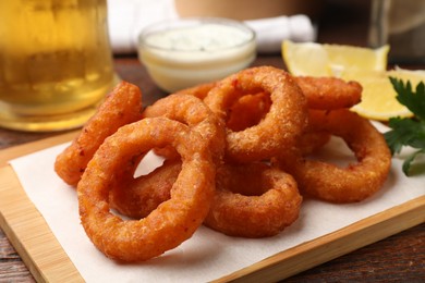 Photo of Fried squid rings served on wooden table, closeup