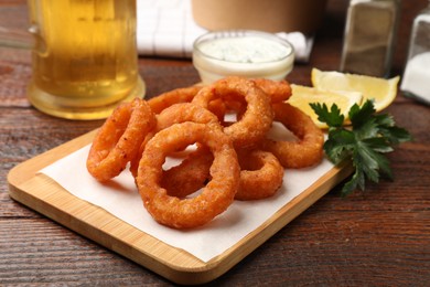 Photo of Fried squid rings served on wooden table, closeup