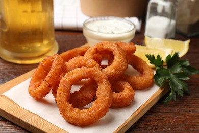 Photo of Fried squid rings served on wooden table, closeup