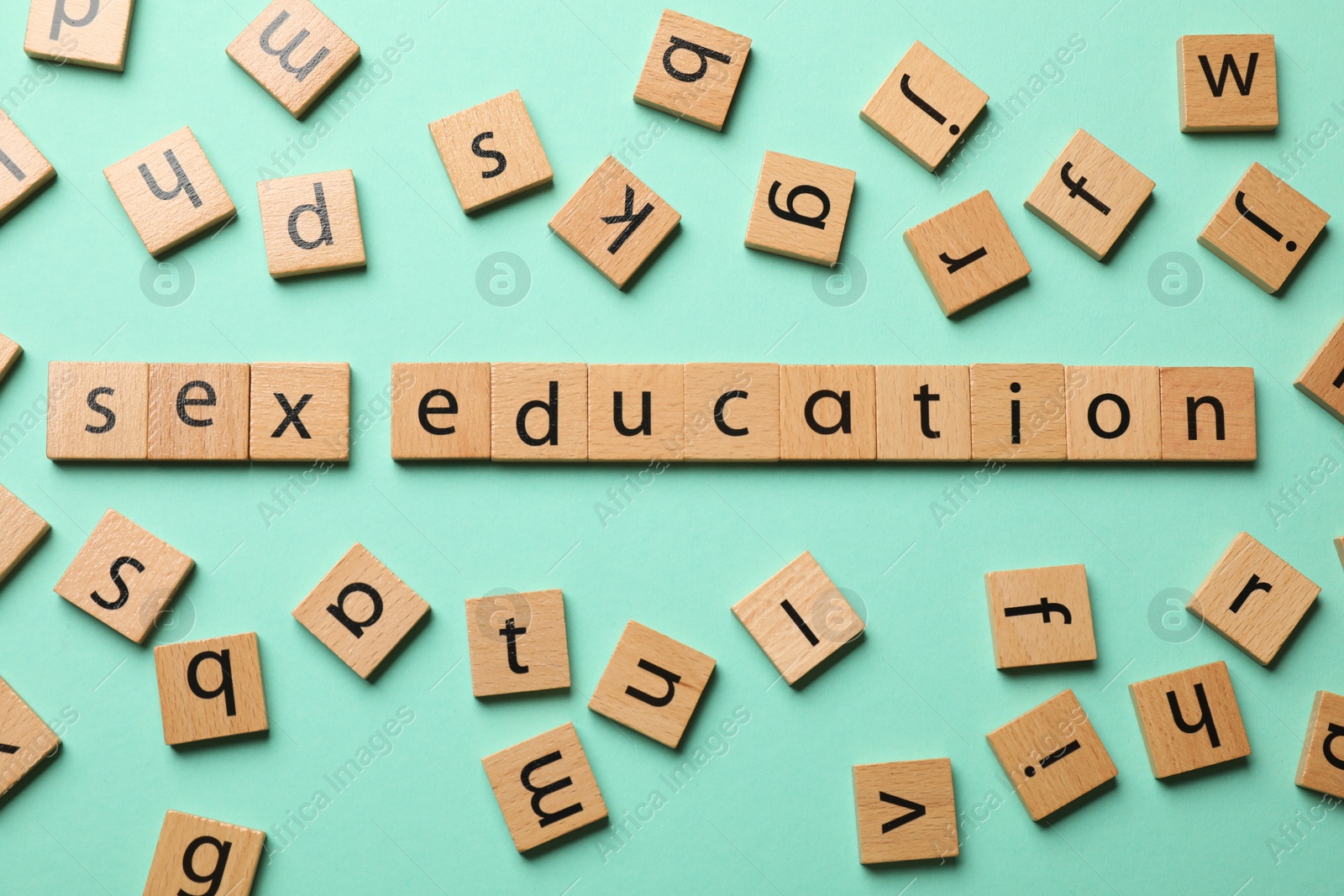 Photo of Words Sex Education made of wooden squares with letters on turquoise background, flat lay
