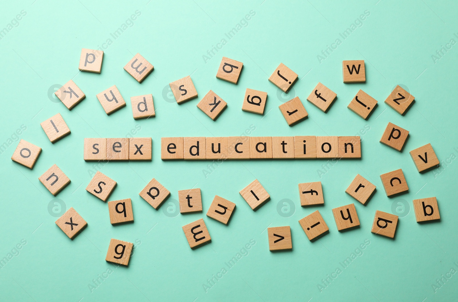 Photo of Words Sex Education made of wooden squares with letters on turquoise background, flat lay