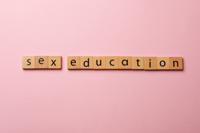 Photo of Words Sex Education made of wooden squares on pink background, flat lay