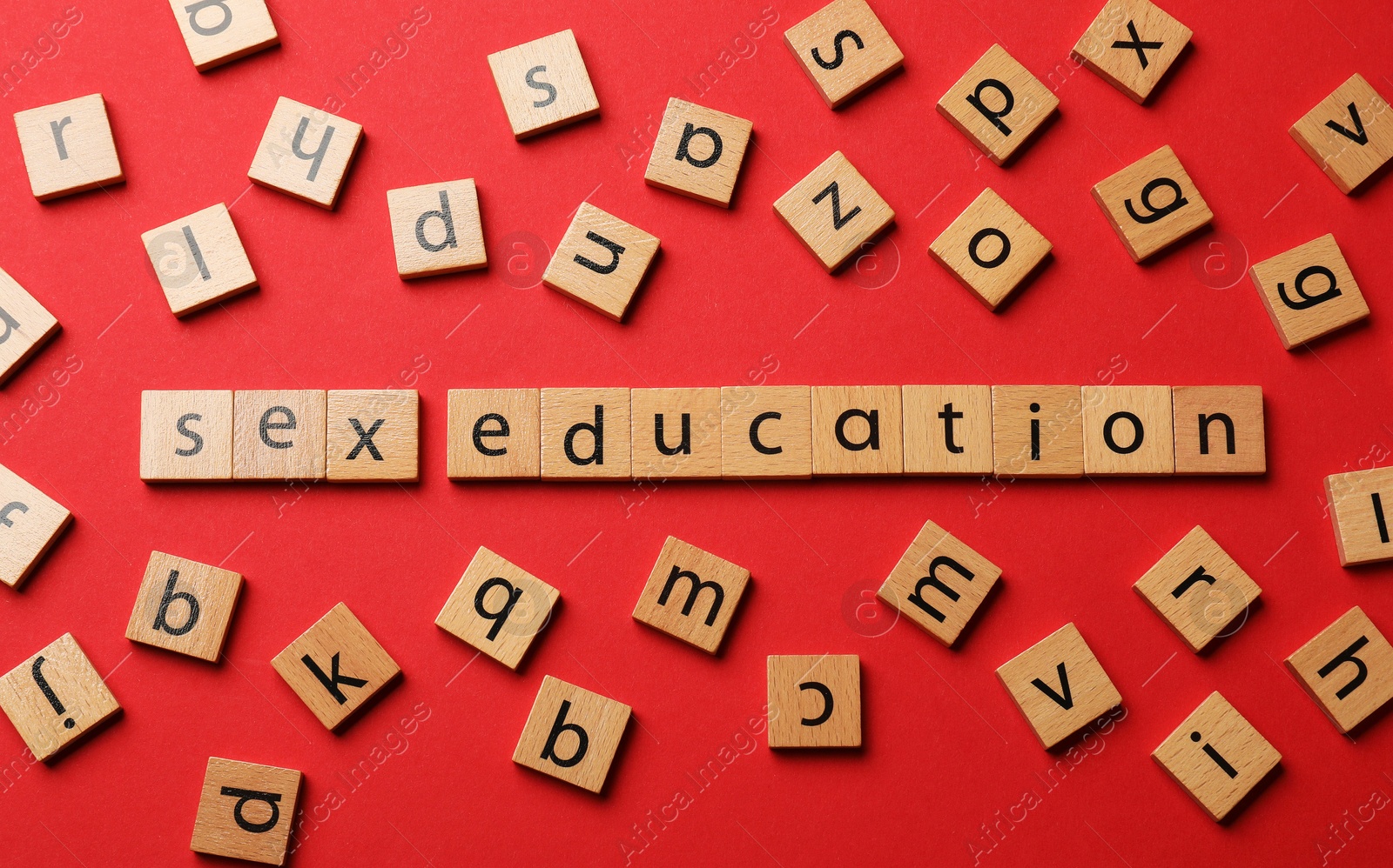 Photo of Words Sex Education made of wooden squares with letters on red background, flat lay