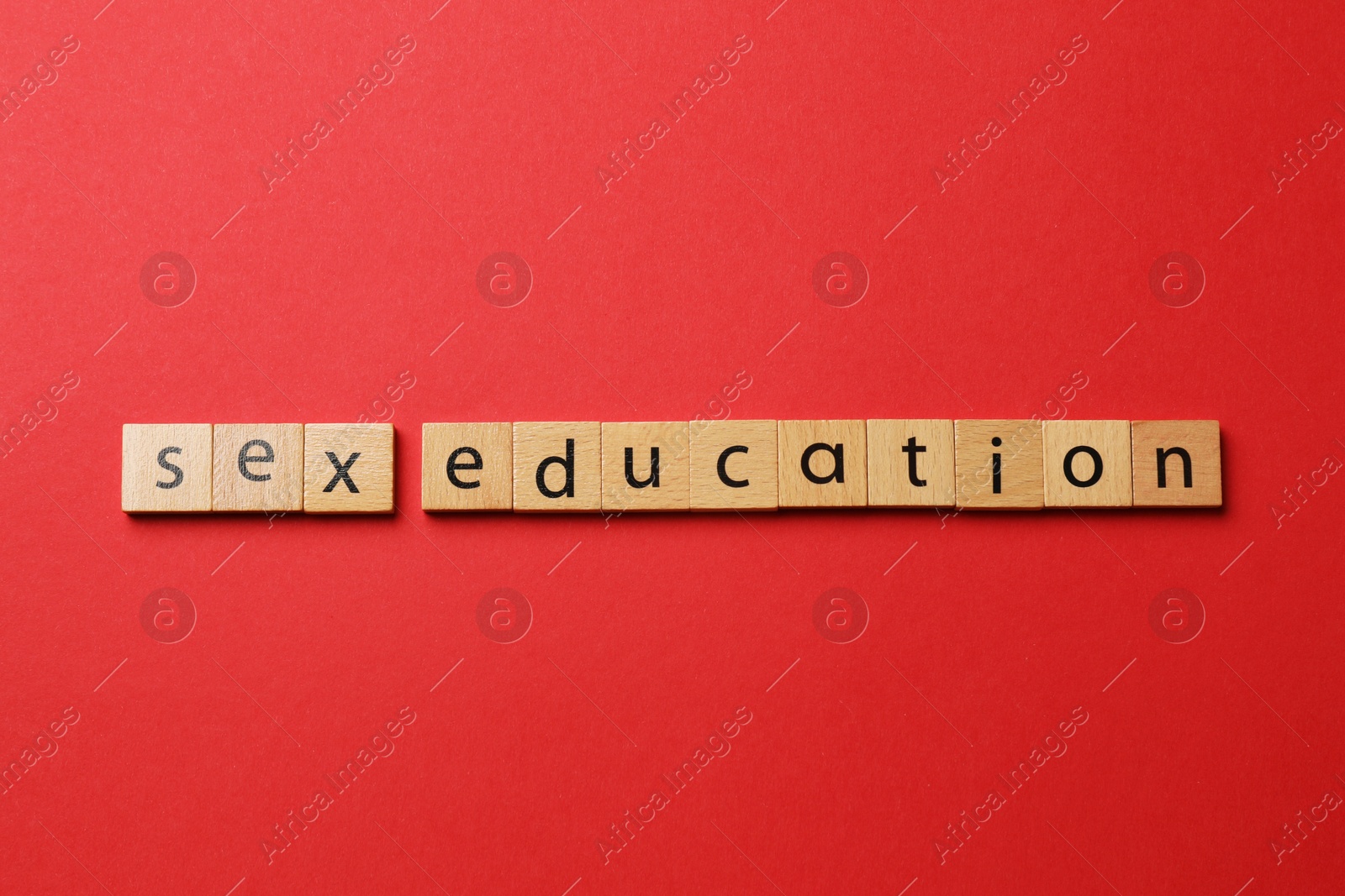 Photo of Words Sex Education made of wooden squares on red background, flat lay