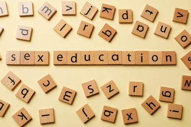 Photo of Words Sex Education made of wooden squares with letters on beige background, flat lay