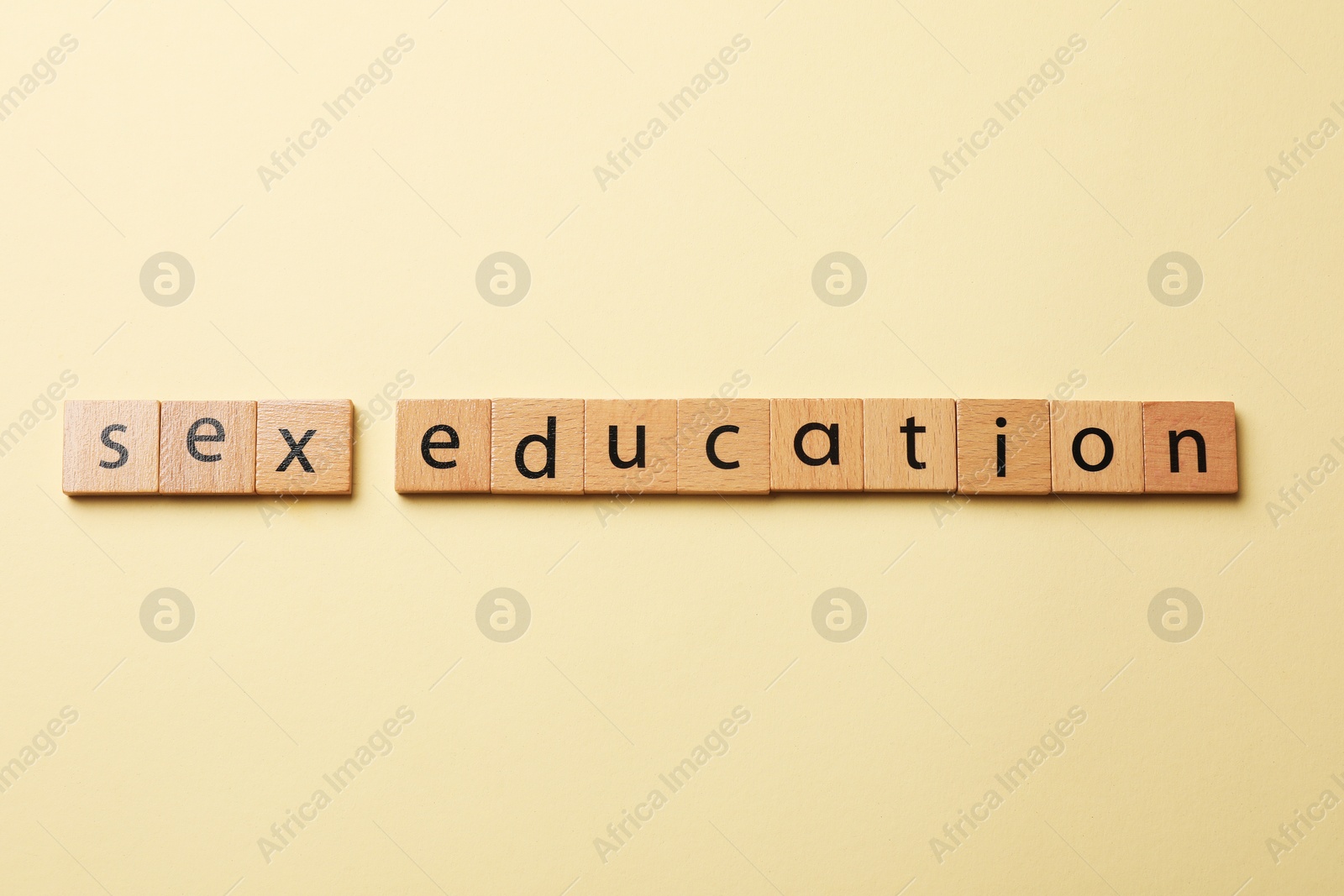 Photo of Words Sex Education made of wooden squares with letters on beige background, flat lay