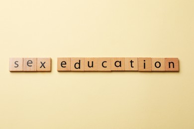 Photo of Words Sex Education made of wooden squares with letters on beige background, flat lay