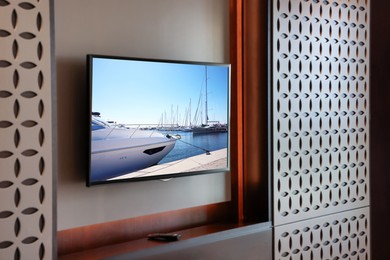Image of TV set with boats near pier on screen in room
