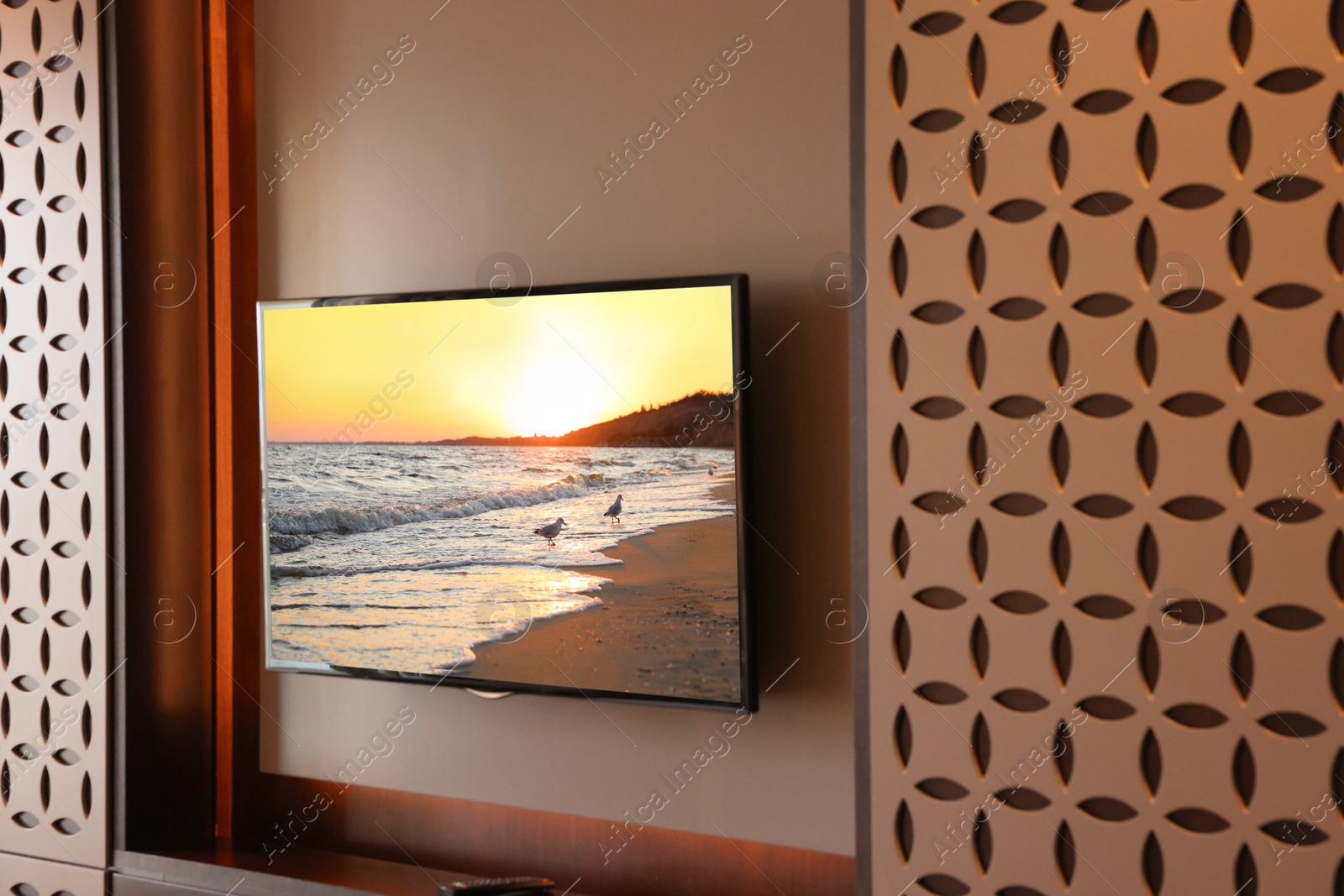 Image of TV set with sunset seascape on screen in room