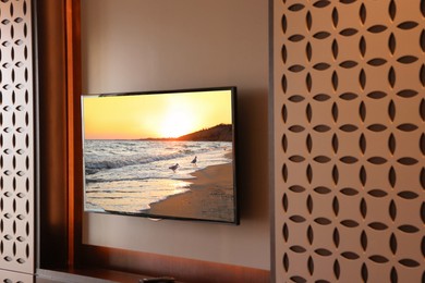 Image of TV set with sunset seascape on screen in room
