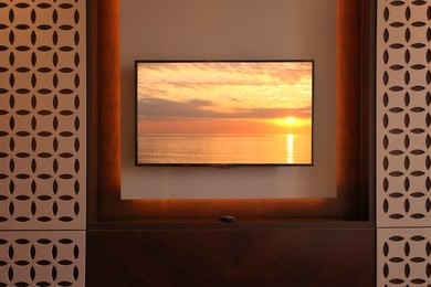 Image of TV set with sunset seascape on screen in room