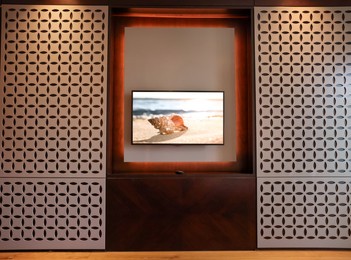 Image of TV set with seashell near ocean on screen in room