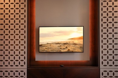 Image of TV set with sunset seascape on screen in room