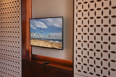 Image of TV set mounted on wall in room. Seascape with seagulls on screen