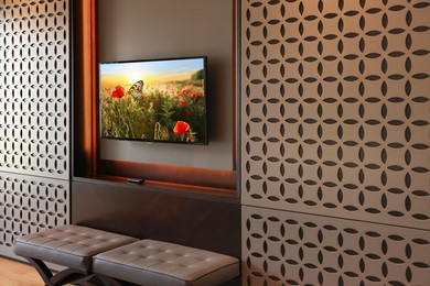 Image of TV set mounted on wall in room. Flowers and butterfly on screen