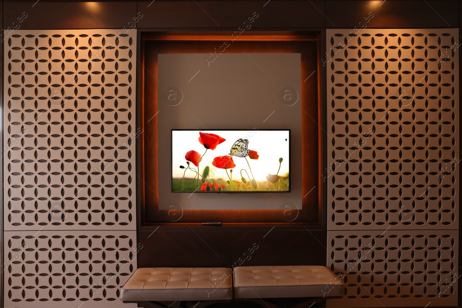 Image of TV set mounted on wall in room. Flowers and butterfly on screen