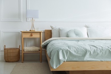 Photo of Bedside table with lamp and glass of water near bed indoors
