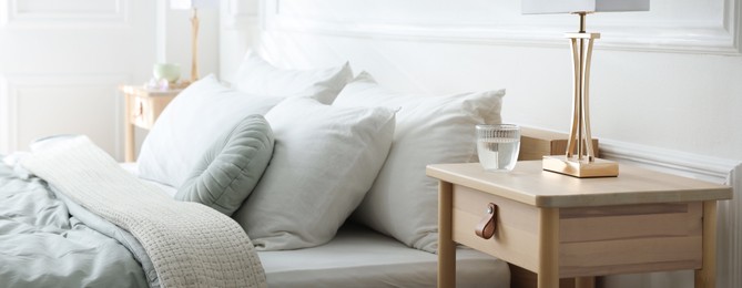 Photo of Bedside tables with lamps near bed indoors