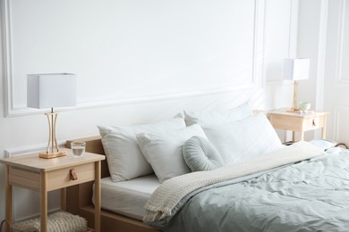 Photo of Bedside tables with lamps near bed indoors
