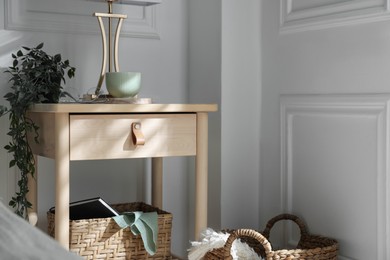 Photo of Bedside table with lamp and other decor near bed indoors
