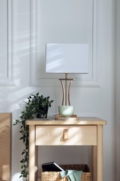 Photo of Bedside table with lamp and other decor near bed indoors