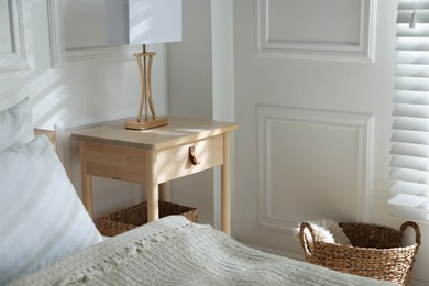 Photo of Bedside table with lamp near bed indoors