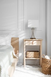 Photo of Bedside table with lamp near bed indoors