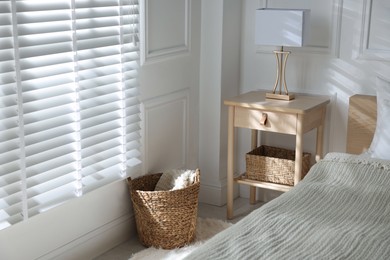 Photo of Bedside table with lamp near bed indoors