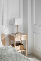 Photo of Bedside table with lamp near bed indoors
