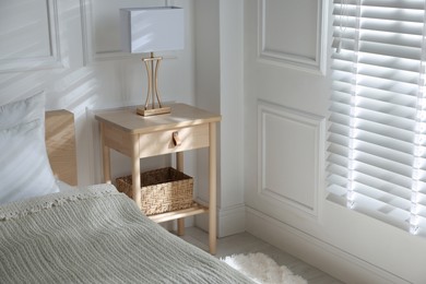 Photo of Bedside table with lamp near bed indoors