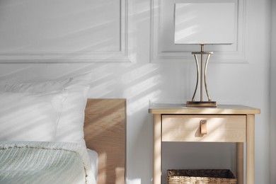 Photo of Bedside table with lamp near bed indoors