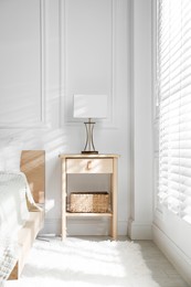 Photo of Bedside table with lamp near bed indoors