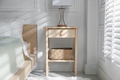 Photo of Bedside table with lamp near bed indoors