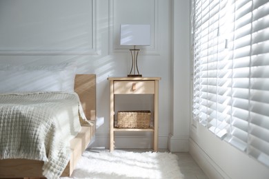 Photo of Bedside table with lamp near bed indoors
