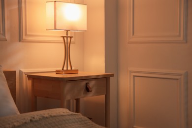 Photo of Bedside table with lamp near bed indoors