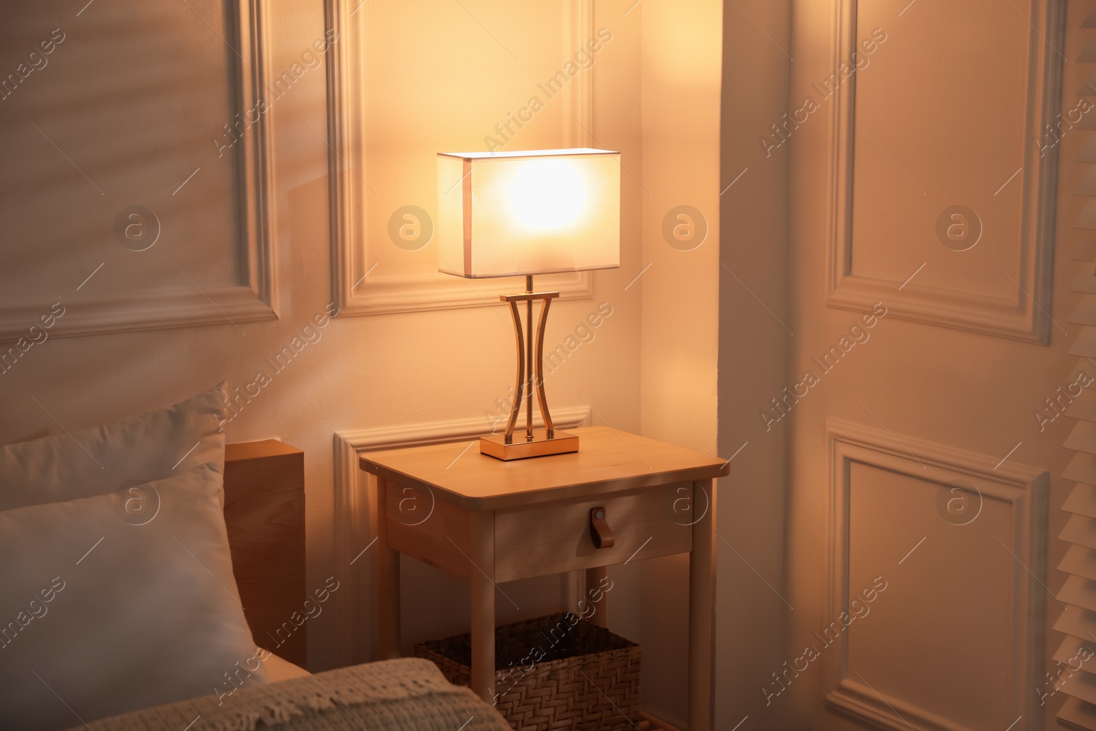 Photo of Bedside table with lamp near bed indoors