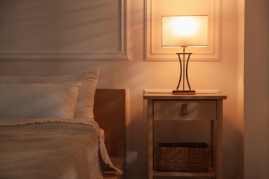 Photo of Bedside table with lamp near bed indoors