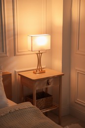 Photo of Bedside table with lamp near bed indoors