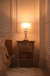 Photo of Bedside table with lamp near bed indoors