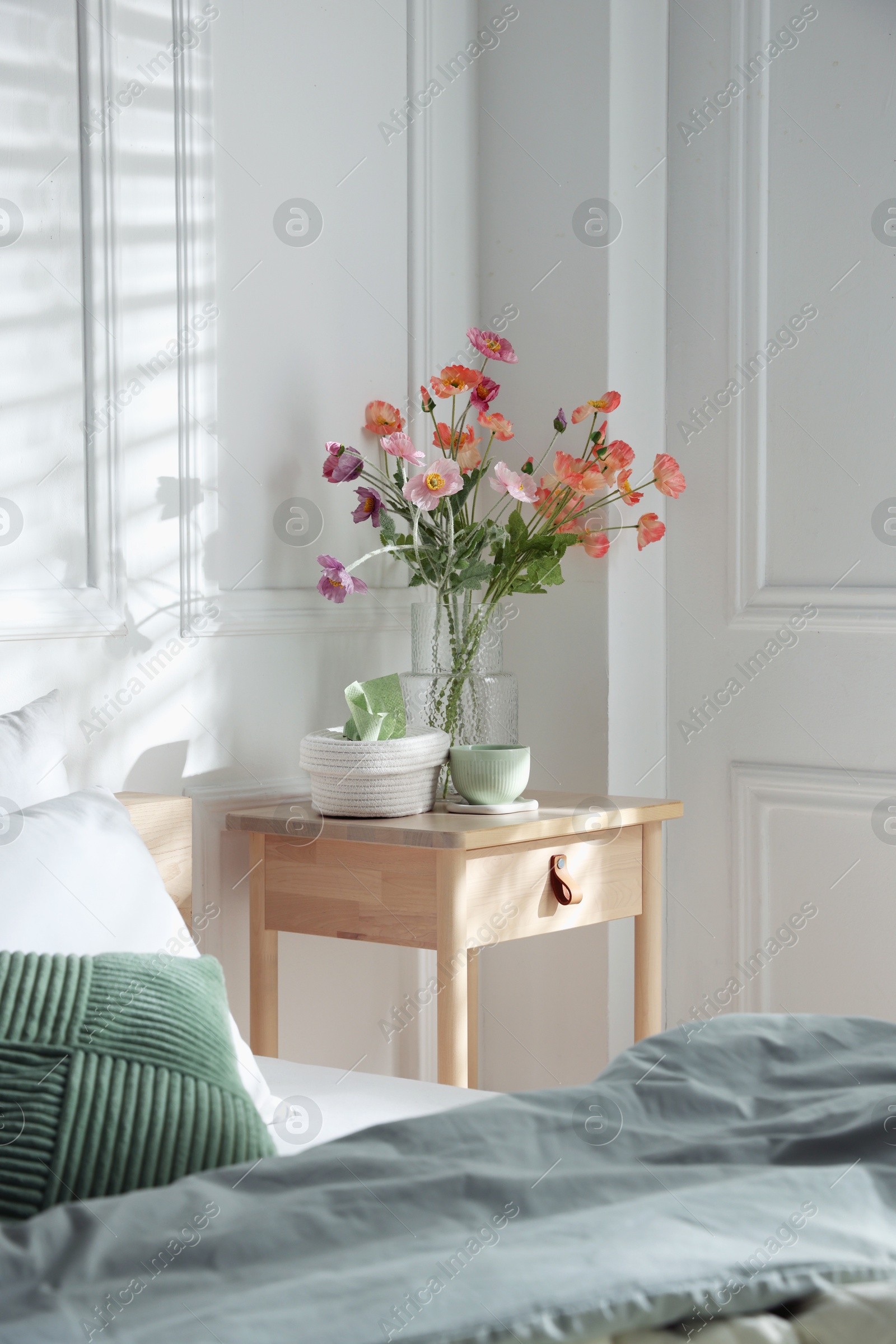 Photo of Bedside table with different decor near bed indoors