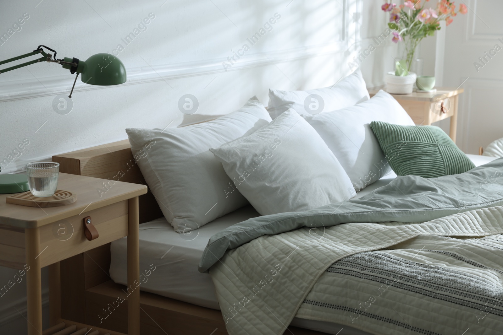 Bedside tables with decor near bed indoors Photo of Bedside tables with decor near bed indoors