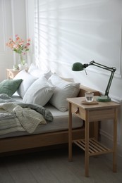 Photo of Bedside tables with decor near bed indoors