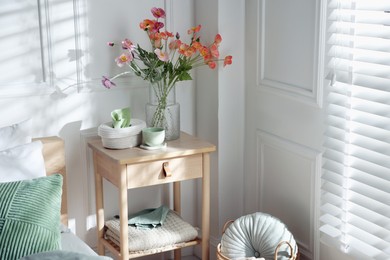 Photo of Bedside table with different decor near bed indoors