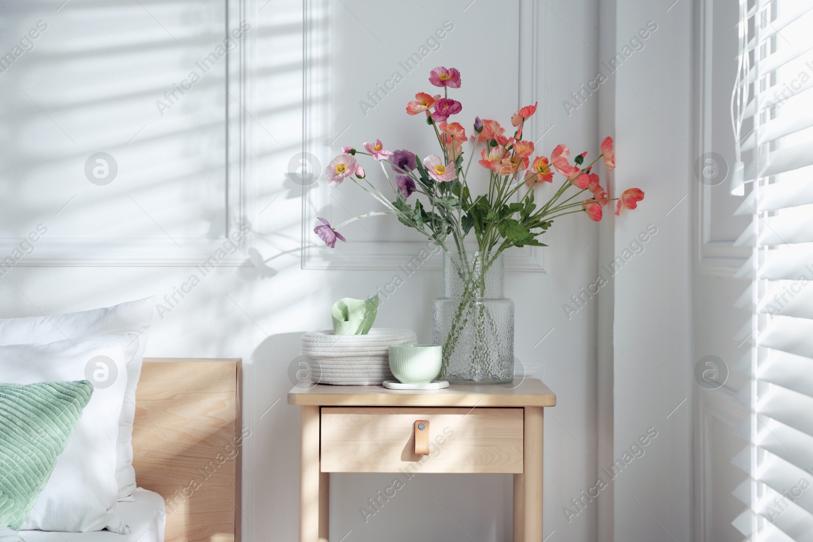 Photo of Bedside table with different decor near bed indoors