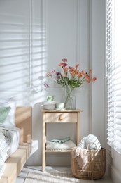 Photo of Bedside table with different decor near bed indoors